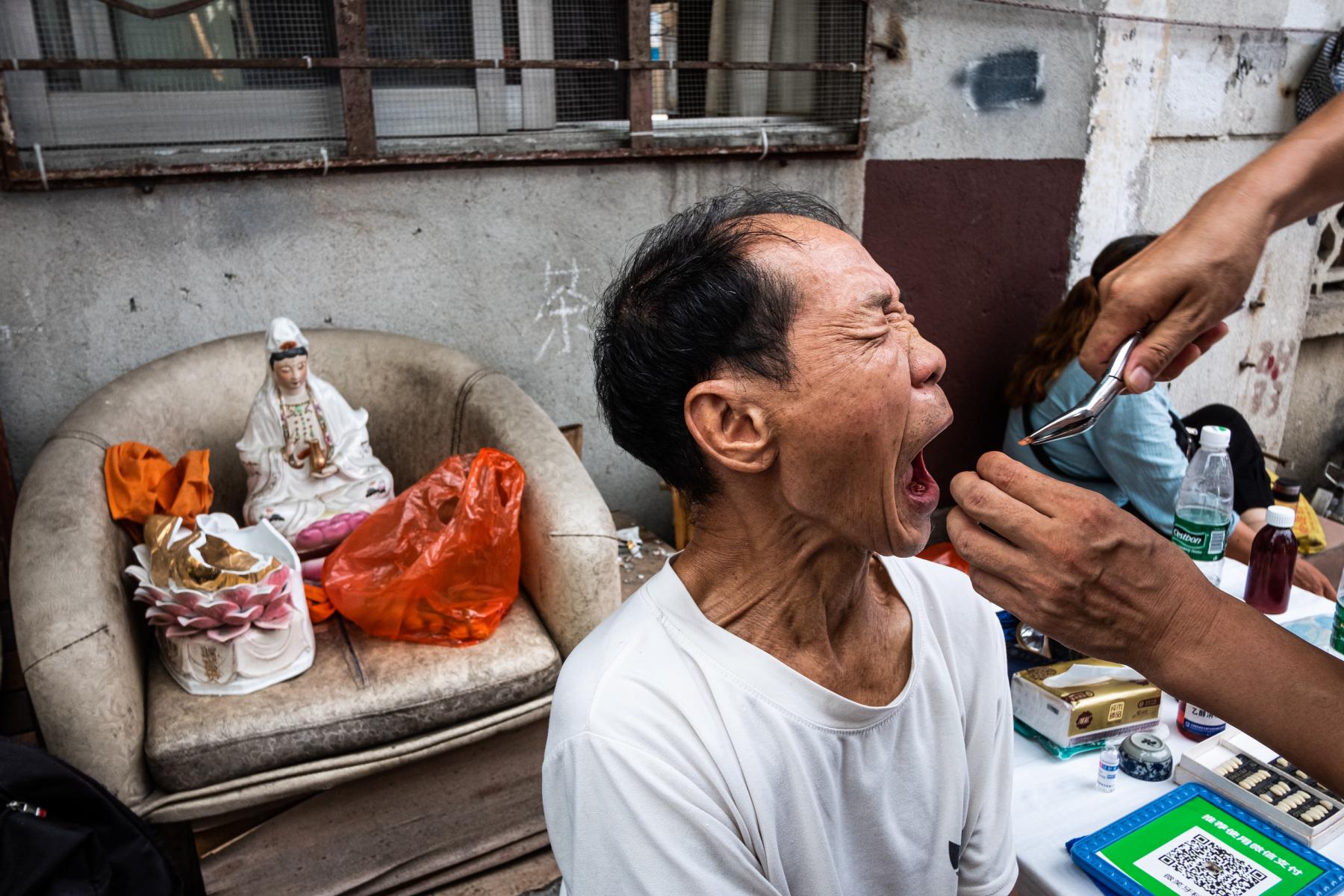 hk_c_二言大俠  今時今日的現代社會，廣東佛山還能找到街頭拔牙的蹤影。當牙齒被拔出的瞬間，這位大叔的臉上彷彿寫着一個“痛”字。.jpg